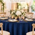 Nappe ronde bleu marine joliment drapée sur une table décorée pour un mariage.